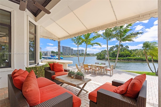 view of patio / terrace featuring a water view, an outdoor living space, outdoor dining space, and ceiling fan