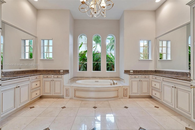 bathroom featuring healthy amount of natural light, a chandelier, a bath, and a towering ceiling