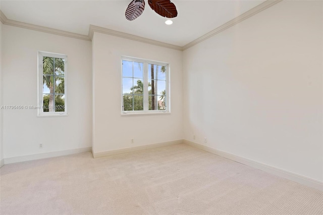 empty room featuring light carpet, baseboards, crown molding, and a ceiling fan