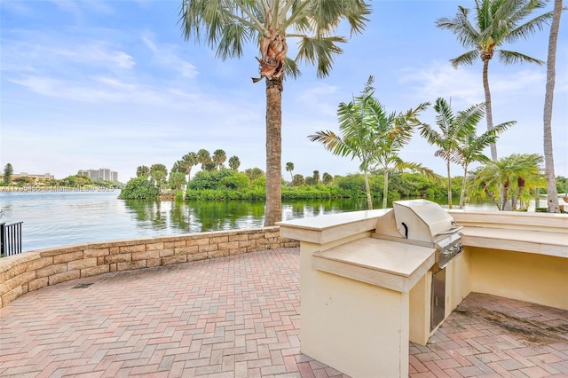 view of patio featuring exterior kitchen, a water view, and grilling area