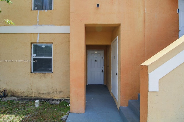 doorway to property featuring stucco siding