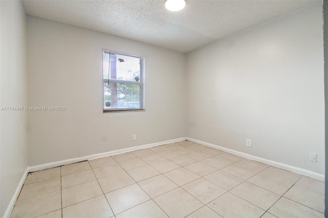 empty room with baseboards, light tile patterned flooring, and a textured ceiling