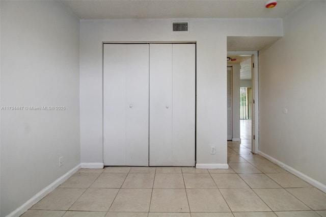 unfurnished bedroom featuring a closet, baseboards, light tile patterned flooring, and visible vents