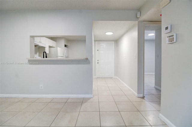 hallway with light tile patterned floors and baseboards