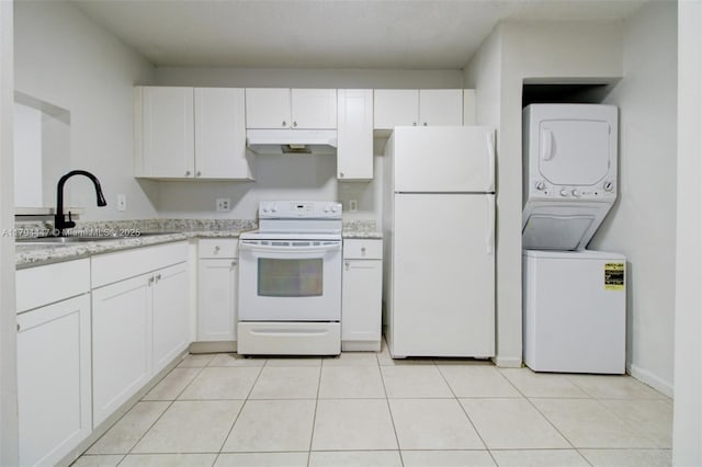 kitchen with white appliances, stacked washing maching and dryer, white cabinetry, under cabinet range hood, and a sink