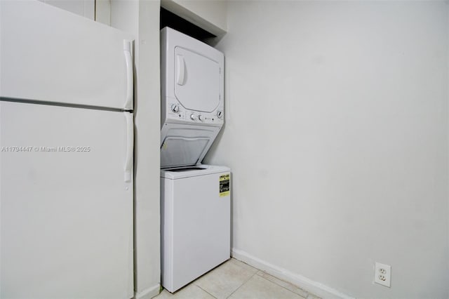 washroom with light tile patterned floors, baseboards, laundry area, and stacked washer and dryer