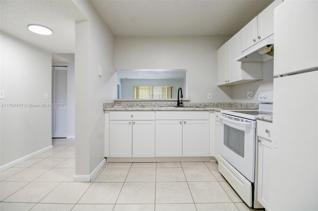 kitchen with a sink, under cabinet range hood, white appliances, and light tile patterned flooring