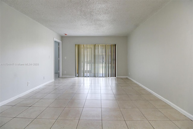 spare room with baseboards, light tile patterned flooring, and a textured ceiling