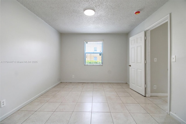 unfurnished room featuring baseboards, light tile patterned flooring, and a textured ceiling