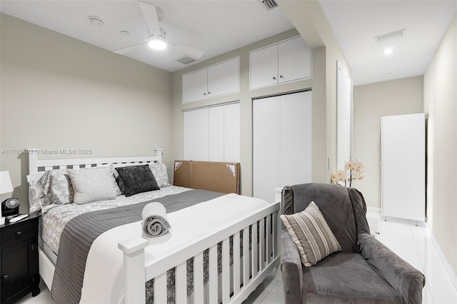 bedroom featuring two closets, light tile patterned flooring, and visible vents