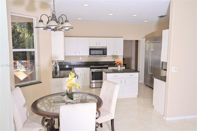 6777 NW 44th Ct, Coral Springs, FL 33067 - kitchen featuring hanging light fixtures, a chandelier, stainless steel appliances, white cabinetry, and a kitchen island