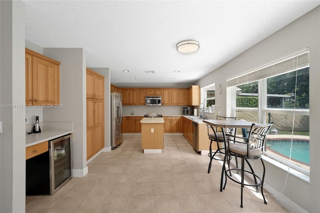 2093 NW 208th Ter, Pembroke Pines, FL 33029 - kitchen with a kitchen island, appliances with stainless steel finishes, a sink, light countertops, and wine cooler