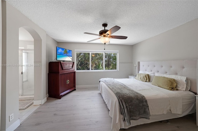 2093 NW 208th Ter, Pembroke Pines, FL 33029 - bedroom with light wood finished floors, arched walkways, a textured ceiling, a ceiling fan, and baseboards