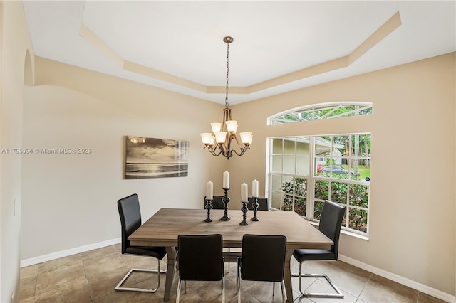 dining room with baseboards, a notable chandelier, and a raised ceiling