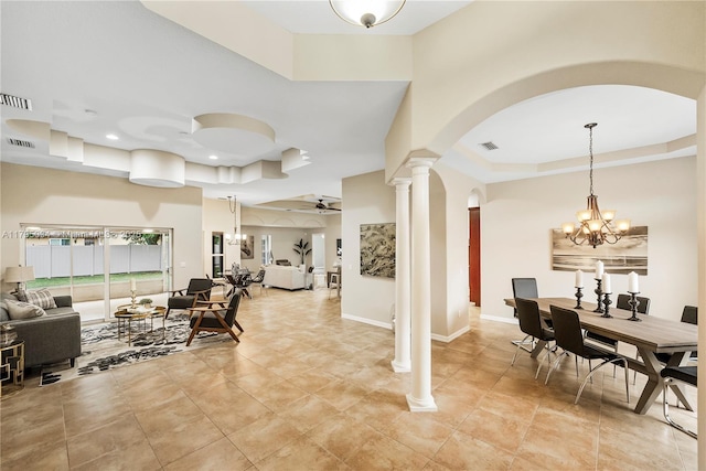 interior space featuring visible vents, decorative columns, a tray ceiling, arched walkways, and ceiling fan with notable chandelier