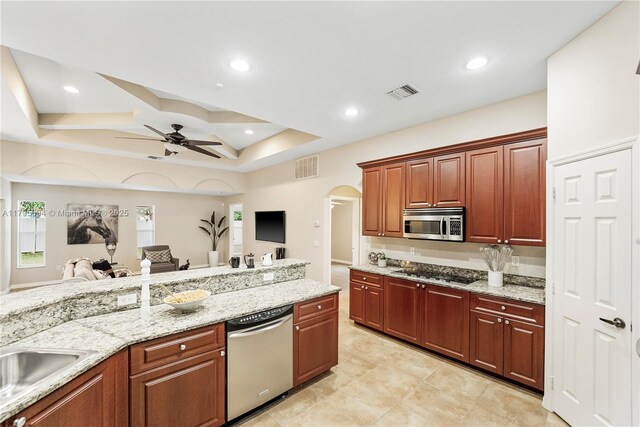 kitchen with ceiling fan, visible vents, arched walkways, stainless steel appliances, and a tray ceiling