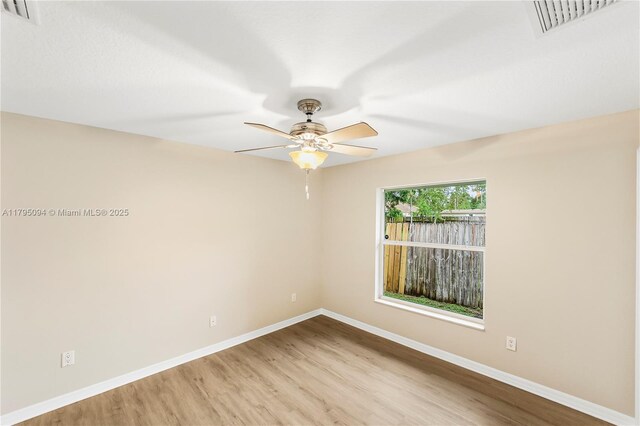 unfurnished room with baseboards, ceiling fan, wood finished floors, and visible vents