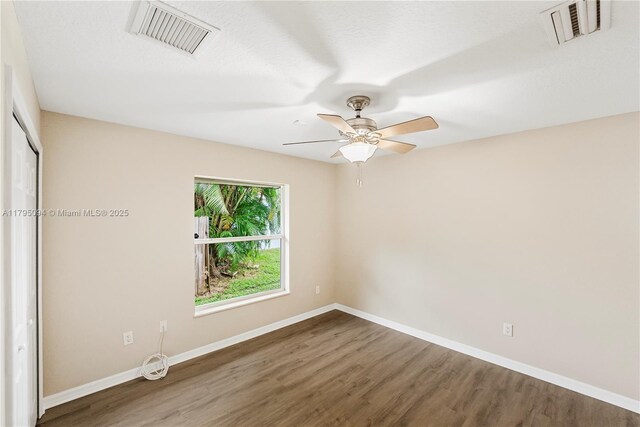 spare room with baseboards, wood finished floors, and visible vents