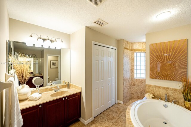 full bath featuring a garden tub, a textured ceiling, visible vents, and vanity