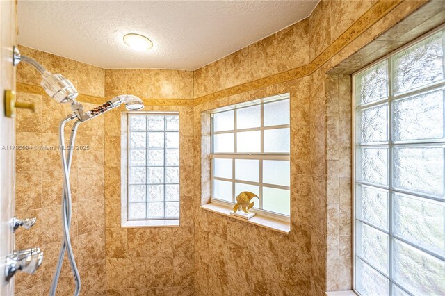 interior details featuring a textured ceiling and walk in shower