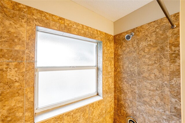 room details featuring a textured ceiling and tiled shower