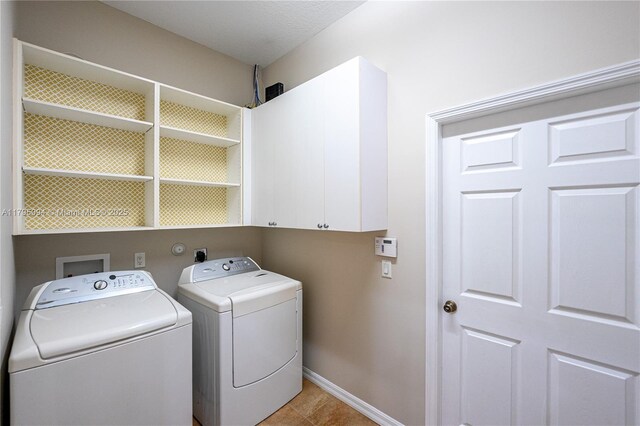 clothes washing area featuring separate washer and dryer, cabinet space, baseboards, and light tile patterned flooring