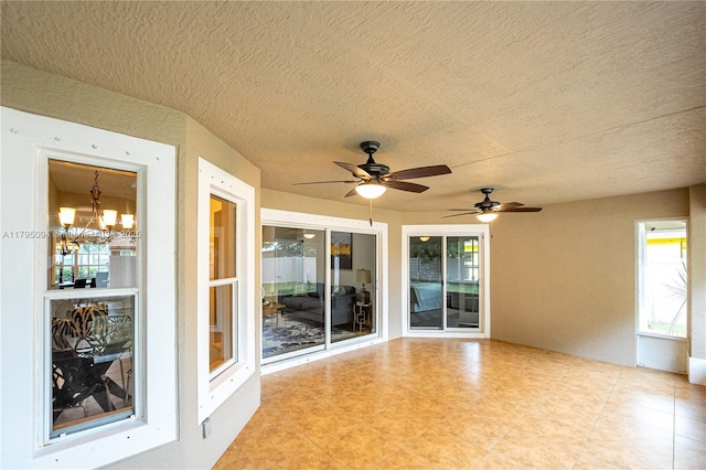 exterior space featuring a textured ceiling, light tile patterned floors, and ceiling fan with notable chandelier