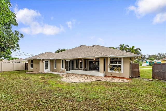 rear view of house featuring fence, stucco siding, a yard, and a patio area