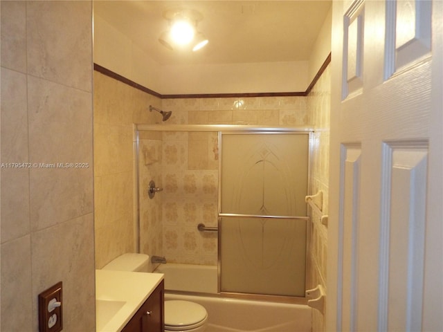 full bathroom with tile walls, vanity, toilet, and shower / bath combination with glass door