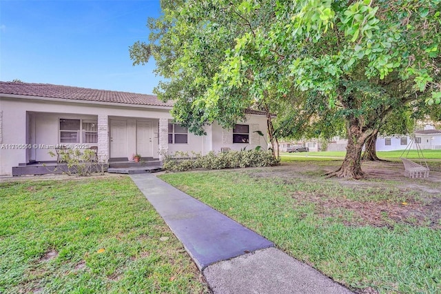 ranch-style house featuring a tiled roof, stucco siding, and a front lawn