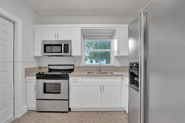 kitchen with light countertops, stainless steel appliances, white cabinetry, and a sink