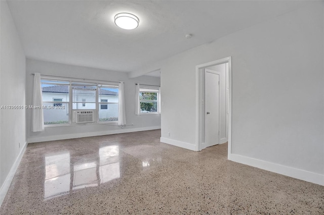 empty room with baseboards, speckled floor, and cooling unit
