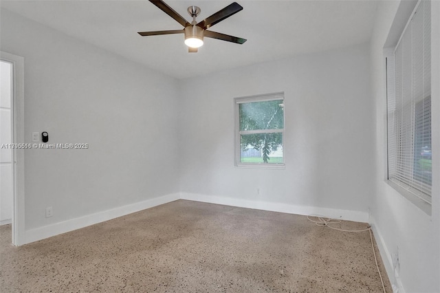 spare room with baseboards, ceiling fan, and speckled floor