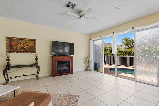 11613 NW 11th Pl, Coral Springs, FL 33071 - living area with visible vents, a glass covered fireplace, baseboards, a ceiling fan, and light tile patterned floors