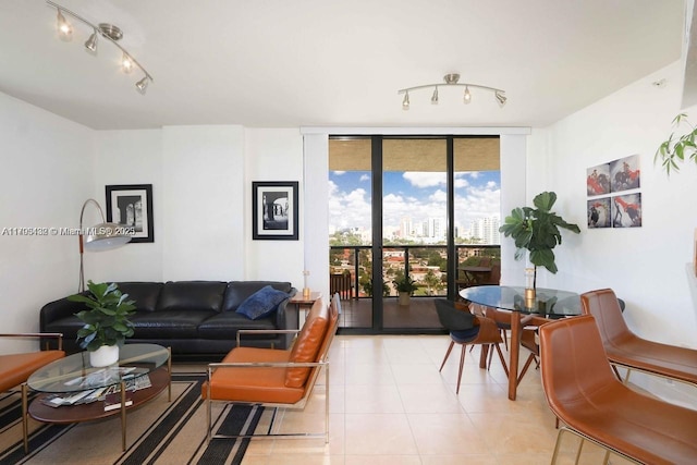 living area with a view of city, rail lighting, light tile patterned floors, and a wall of windows