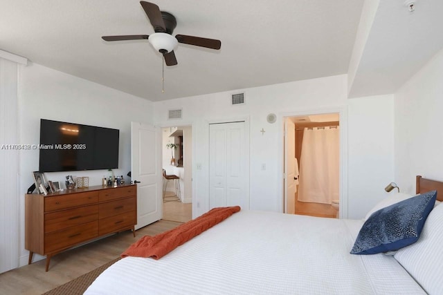 bedroom with ensuite bathroom, a closet, light wood-type flooring, and visible vents
