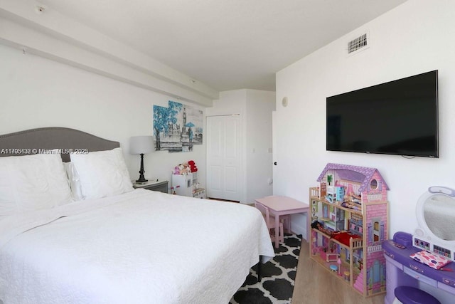 bedroom with a closet, wood finished floors, and visible vents