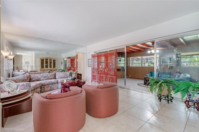 living room featuring a ceiling fan, tile patterned floors, and wooden walls