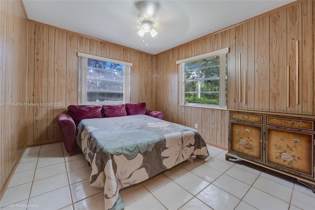 bedroom with wooden walls, light tile patterned flooring, and multiple windows