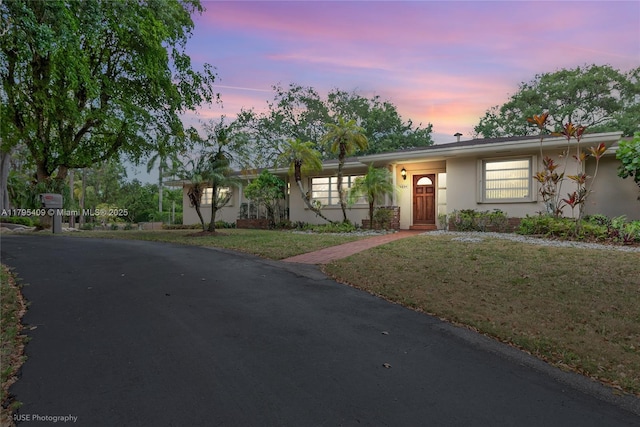 ranch-style house with a lawn and stucco siding