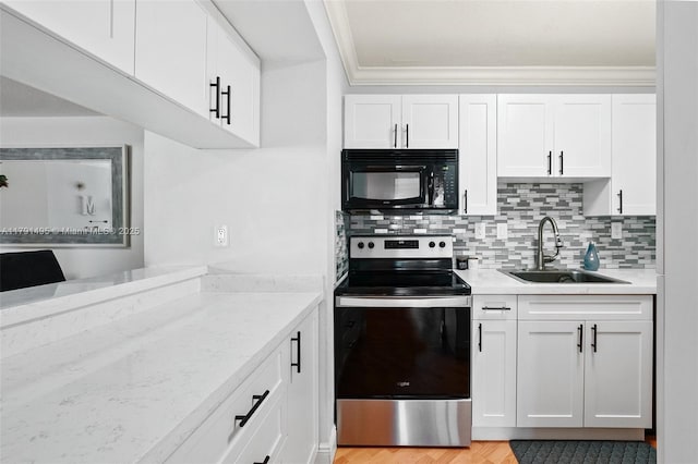 kitchen featuring electric range, black microwave, light countertops, white cabinets, and a sink