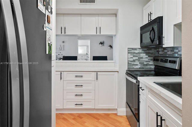 kitchen with visible vents, light countertops, white cabinets, appliances with stainless steel finishes, and backsplash