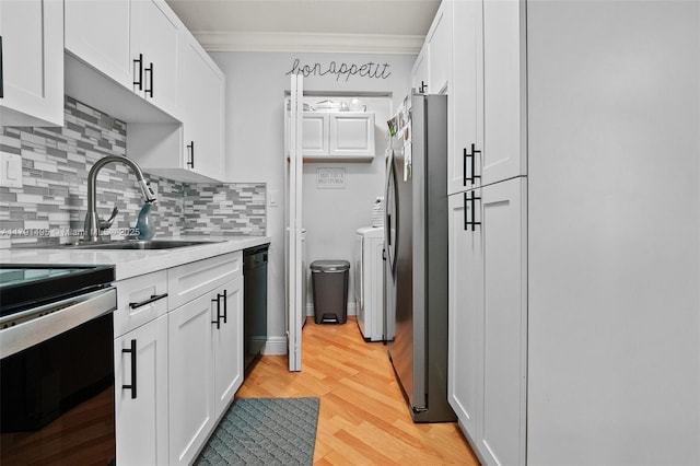 kitchen with decorative backsplash, crown molding, appliances with stainless steel finishes, a sink, and white cabinetry