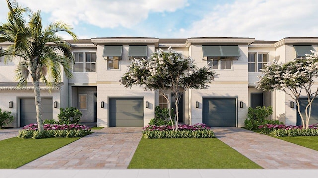 townhome / multi-family property with driveway, a front yard, and a garage