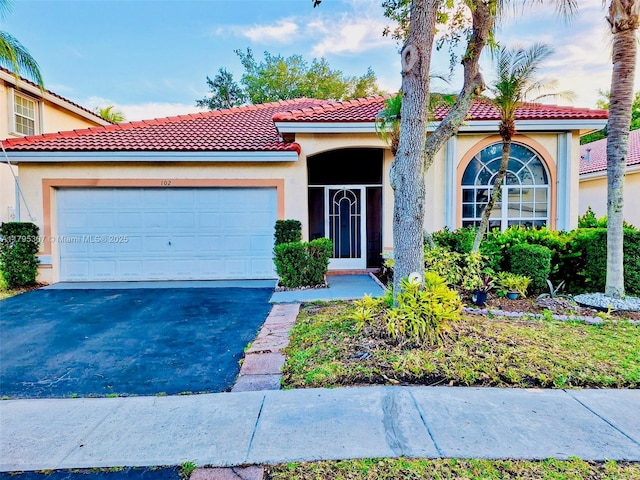 mediterranean / spanish home featuring a garage, driveway, a tile roof, and stucco siding