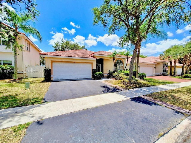 view of front of property with a front lawn, aphalt driveway, stucco siding, an attached garage, and a tile roof