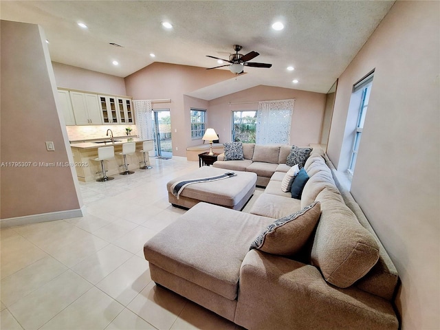living area featuring a healthy amount of sunlight, light tile patterned floors, ceiling fan, and lofted ceiling