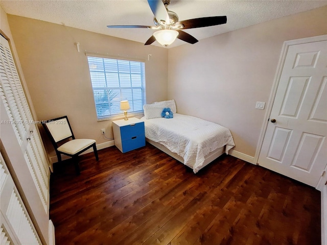 bedroom featuring a textured ceiling, baseboards, and dark wood-type flooring
