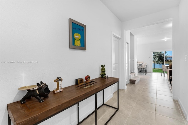 hall featuring baseboards and light tile patterned flooring