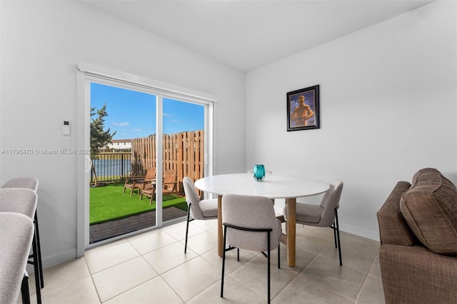 dining space featuring baseboards, a water view, and light tile patterned floors